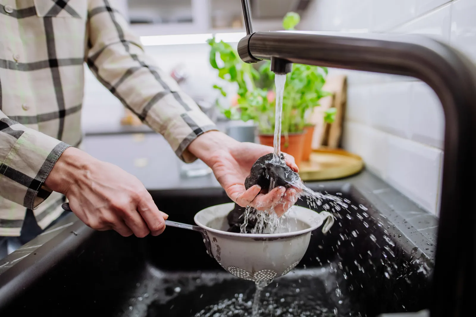 Fresh vegetables being rinsed under a kitchen tap in bright natural light — much of our daily mineral intake comes from the food we cook, which is why the water it touches matters