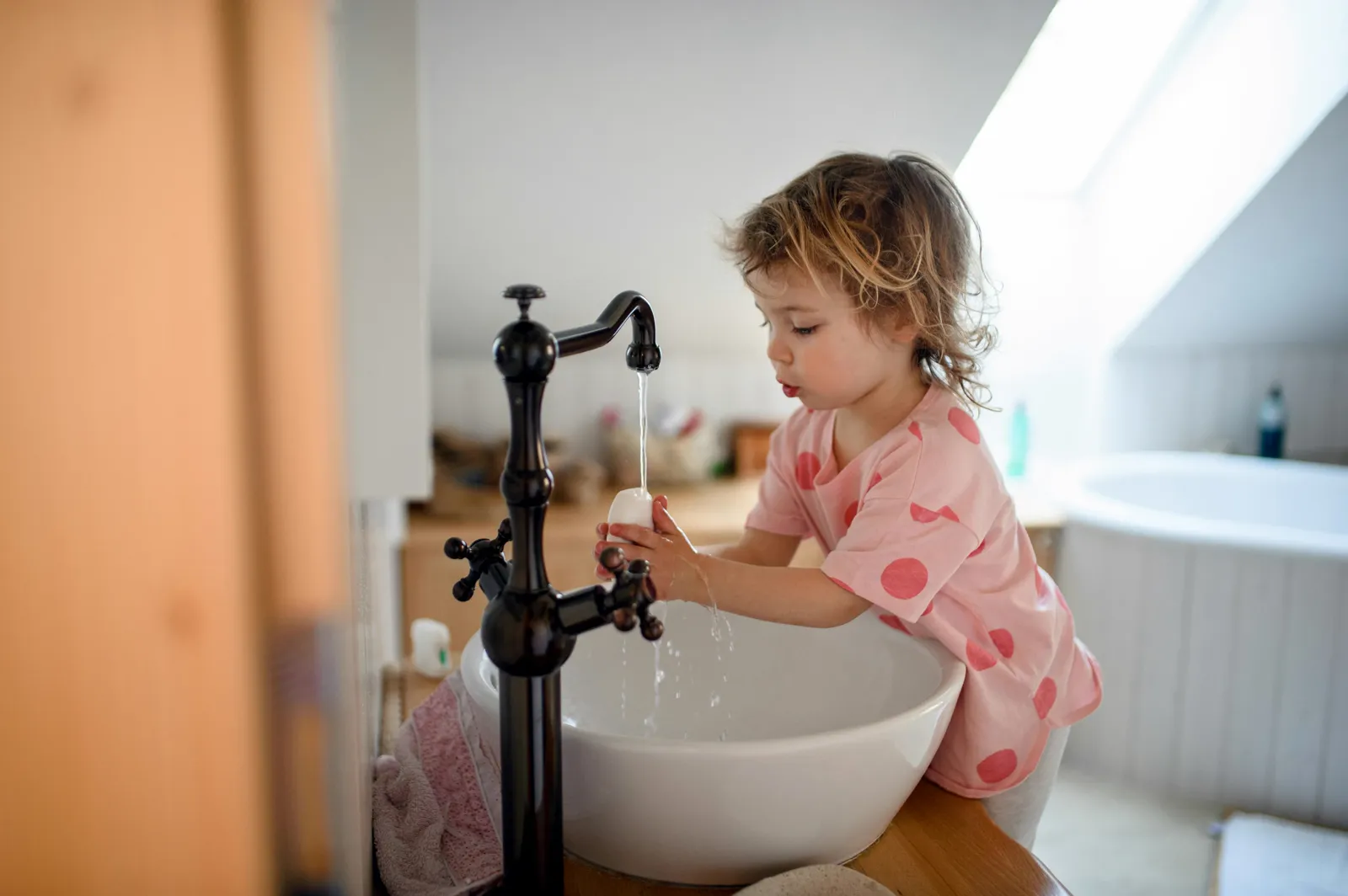 Young child at the kitchen faucet — children are among those the EPA and ATSDR flag as most sensitive to long-term PFAS exposure