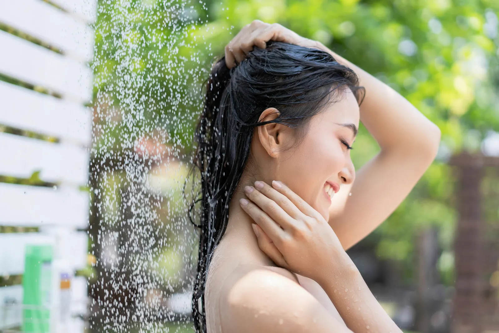 Woman washing her hair at an outdoor shower — the feel of shower water on skin and hair is directly affected by chlorine and mineral content