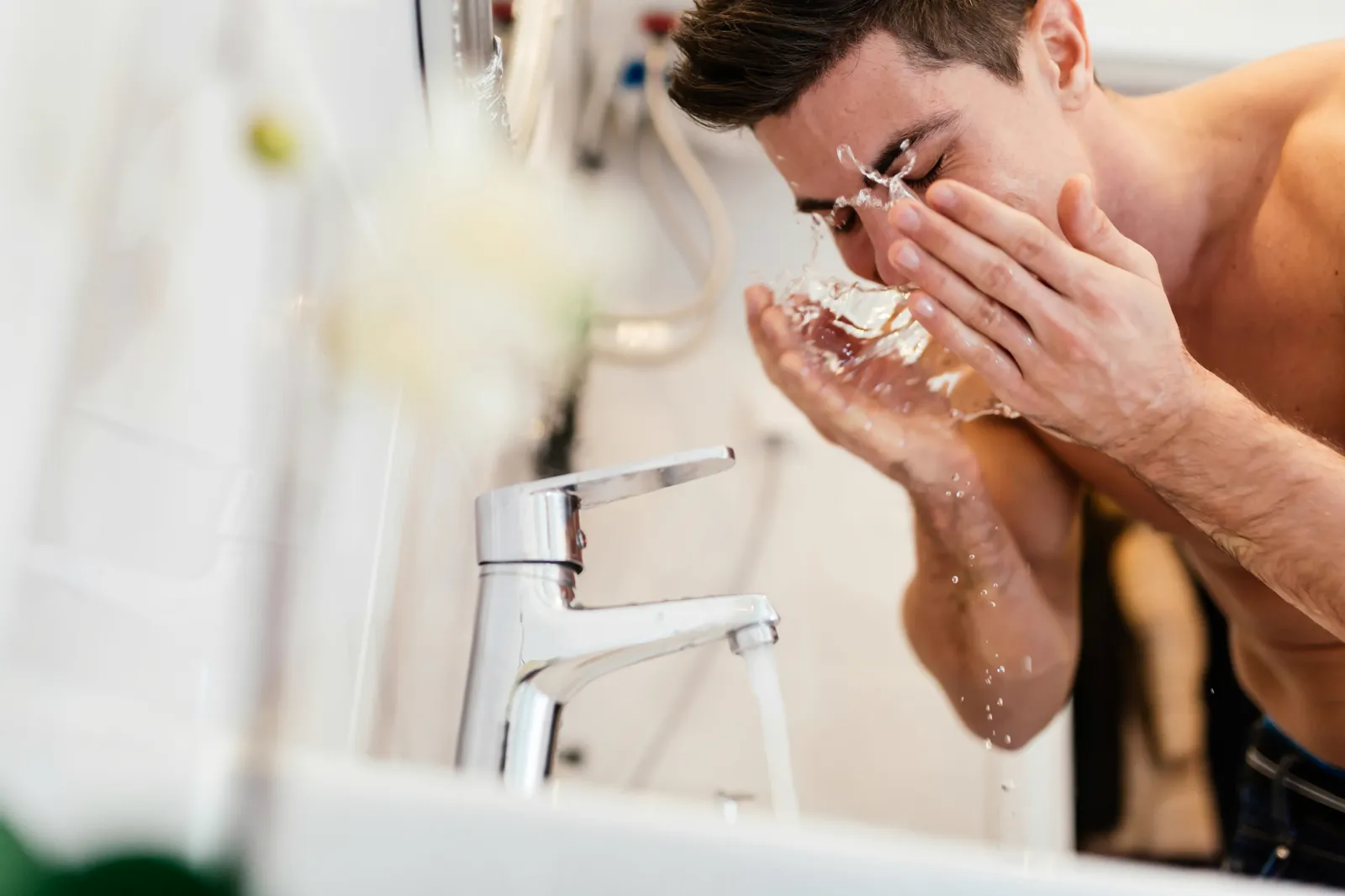 Man washing his face at a bathroom sink — well water quality affects every tap in the home, not just the kitchen