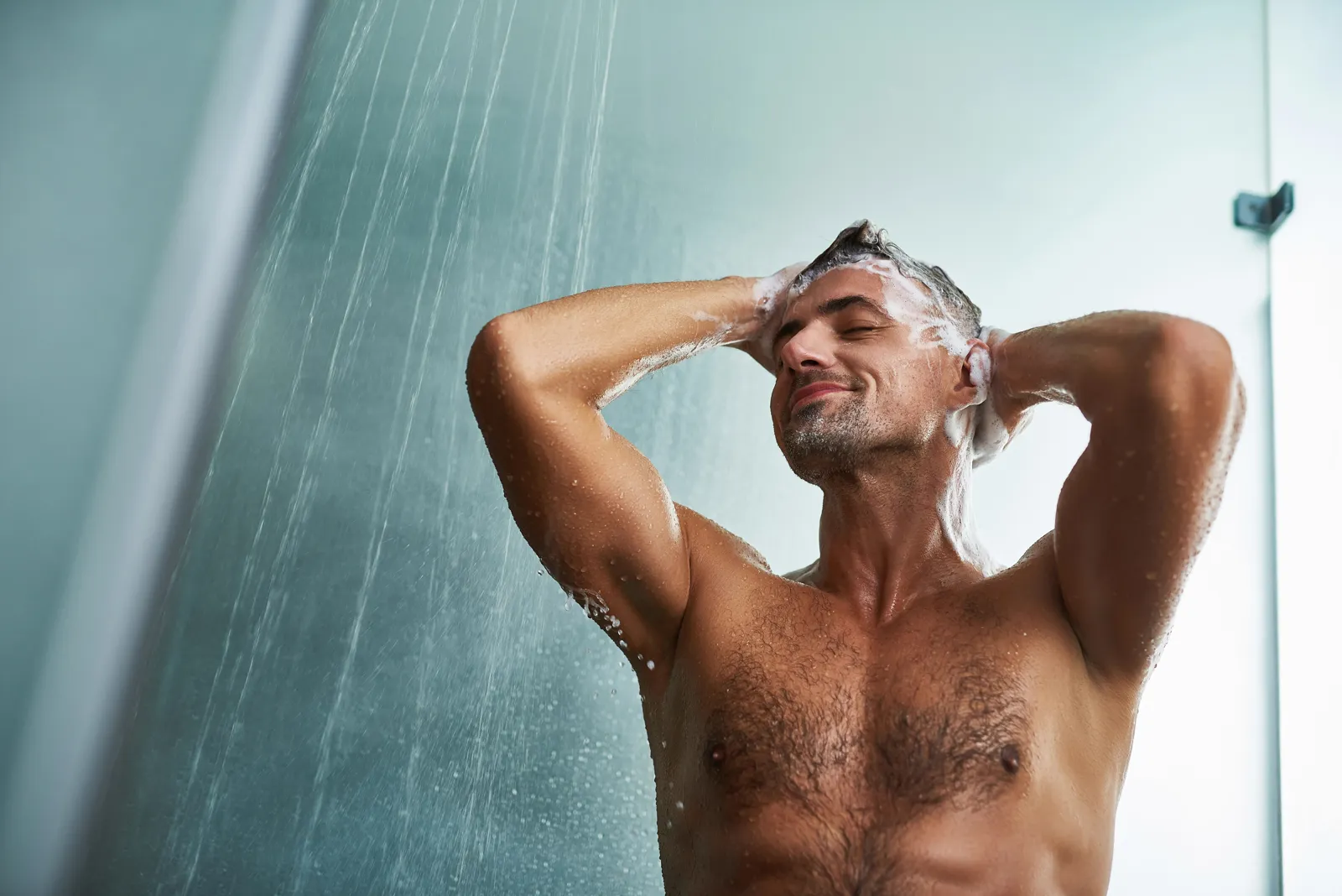 Man showering with his eyes closed, relaxed — a whole-home filter removes chlorine at every fixture including the shower